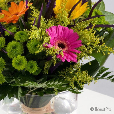 Pink yellow orange green flowers in a glass vase